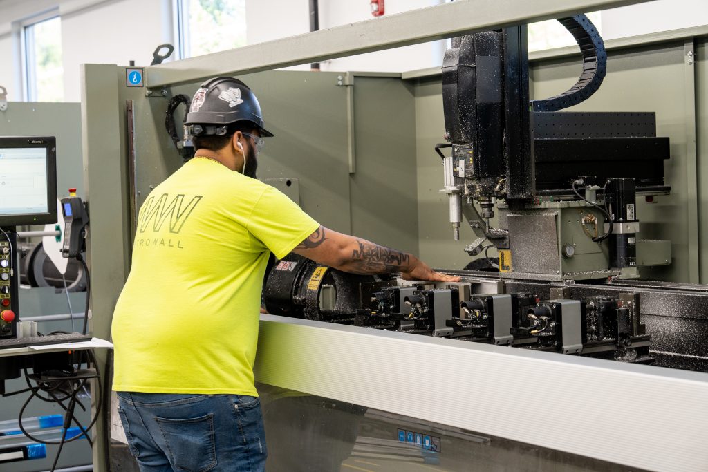 CNC operator loading aluminum stock into the machine to be but. 