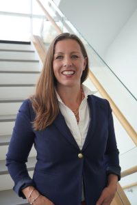 Woman with long hair wearing white shirt and blue blazer. 