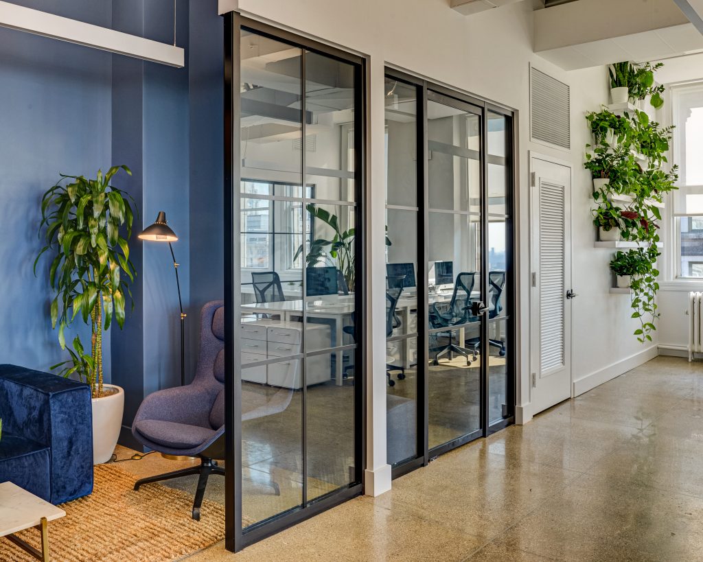 New York space with plants, glass wall interiors, and natural light. 